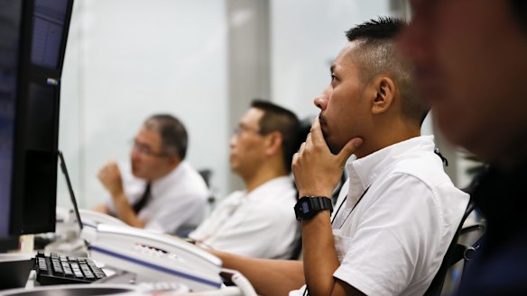 In shock: Employees work in front of computer monitors at a foreign exchange brokerage in Tokyo, Japan, on Friday.