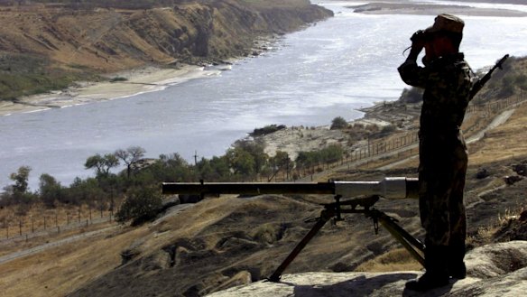 A Russian border guard observes the Afghan territory over the Pyandzh River, controlled by the Afghanistan's Taliban rulers, in 2001.