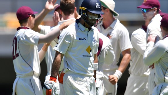 Glenn Maxwell (centre) of Victoria walks off the field after losing his wicket to Brendan Doggett of Queensland.