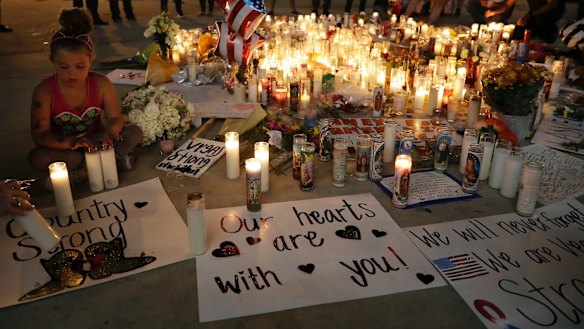 A girl places candles at a memorial in Las Vegas.