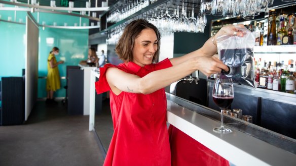 Sommelier Lillia McCabe pouring a glass of wine from a cask at Icebergs Dining Room and Bar in 2020.