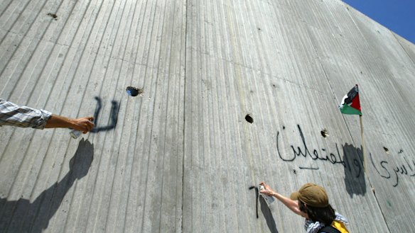 Foreign activists spray graffiti on the wall erected by Israel near the northern West Bank town of Qalqilya, which is also walled off on three sides.