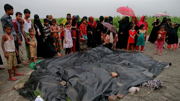 Bangladeshi villagers gather around the covered bodies of Rohingya women and children who died after their boat capsized.
