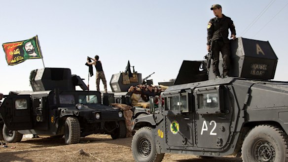 Iraqi special forces soldiers - flying a sectarian Shiite flag from their vehicles - move out to join the Mosul offensive from a camp near Khazer, Iraq, on Friday. 