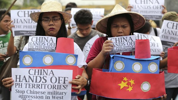Filipino student activists hold mock Chinese ships to protest recent island-building in the South China Sea.