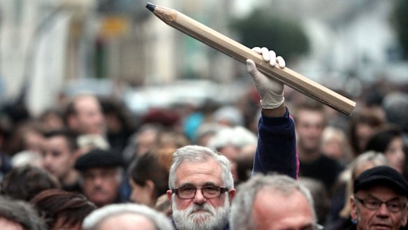 A man holds up a giant pencil during a gathering in Tarbes, southern France, in tribute to the 12 people killed by two gunmen at the editorial office of Charlie Hebdo