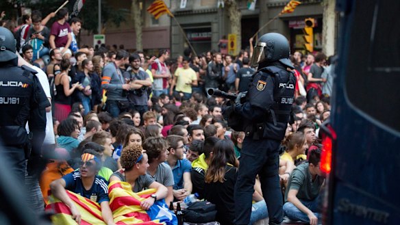 A Spanish national police officer stands guard outside the offices of the left-wing party CUP in Barcelona. Police left after waiting for hours for permission to search the premises for referendum-related propaganda that never arrived.  