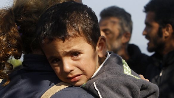 A boy on his mother's shoulder as they enter into Macedonia from Greece on the border  between the two countries on Tuesday. 