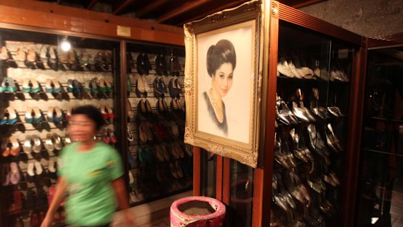 A Marikina Shoe museum worker passes a portrait of former First Lady Imelda Marcos hanging next to hundreds of her shoes in Marikina City, east of Manila, Philippines.