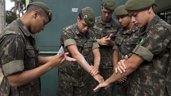 Army soldiers apply insect repellent as they prepare for a clean-up operation against the Aedes aegypti mosquito in Sao Paulo. 