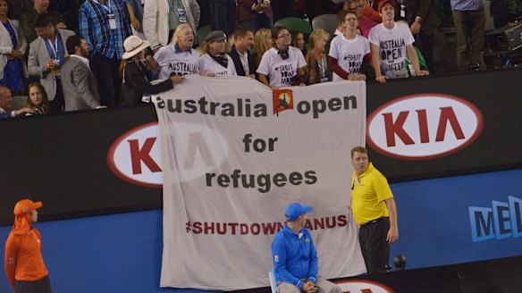 Protesters unfurl a banner during the men's final, drawing attention to the plight of refugees on Manus Island. 