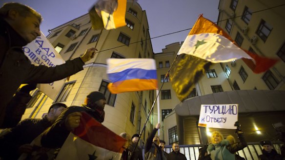 Protesters wave Russian and Syrian flags and signs reading 'Turkey to account!' outside the Turkish embassy in Moscow on Tuesday.