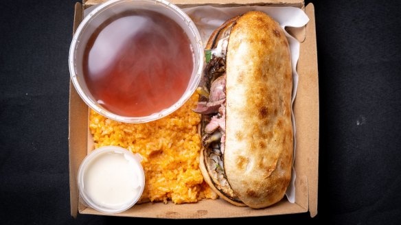 Cheesesteak with consomme and a side of rice.