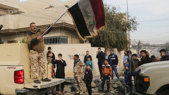 An Iraqi soldier waves the national flag as security forces patrol on the eastern side of Mosul, Iraq, on January 18. 