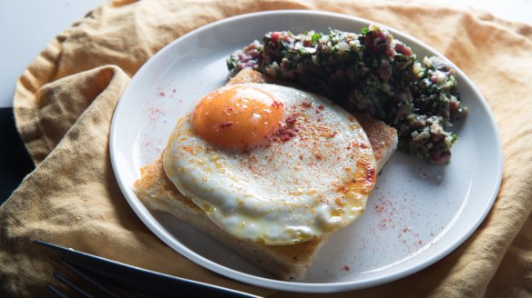 Venison tartare with cheese and bone marrow toastie topped with a fried egg.