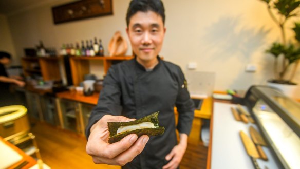 Jimsan (Martin) Kim holding the scallop nigiri.