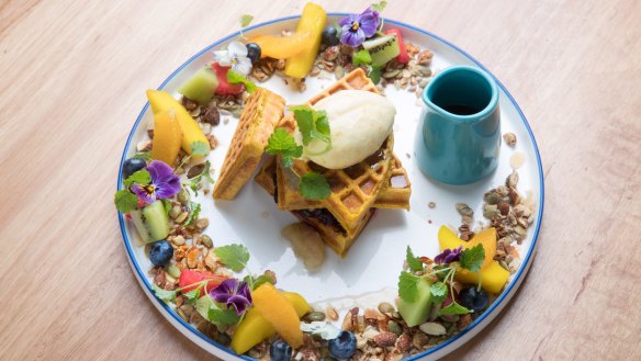 Spiced pumpkin waffle encircled by fruit, nuts and seeds.