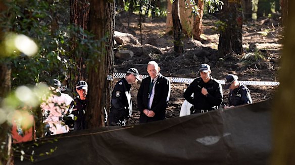 Police watch on as forensic officers comb the burial site near Waterfall.