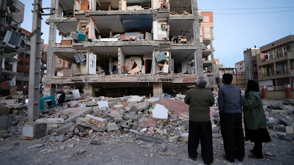 People look at destroyed buildings after an earthquake at the city of Sarpol-e-Zahab in western Iran.