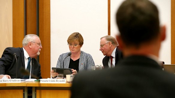 Senators Barry O'Sullivan, Linda Reynolds and Ian Macdonald talk strategy during their interrogation of Solicitor-General Justin Gleeson.