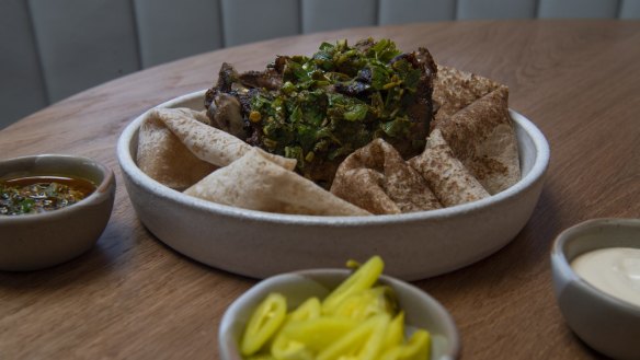 Lamb neck shawarma with tarator, pickles, chermoula and flatbread. 