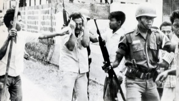 A Chinese student (centre) is pummelled by Indonesian youths who stormed the dormitory of a communist Chinese University in Jakarta in 1965.
