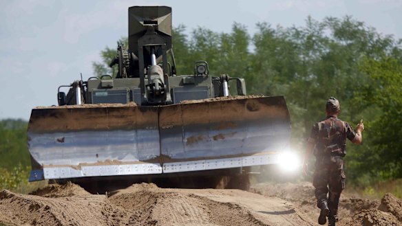 Hungarian army soldiers use a bulldozer as they prepare the land to build a fence along the Hungarian border with Serbia near Morahalom, Hungary.