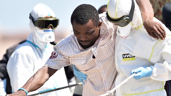 A crew member of the Irish naval vessel LE Niamh helps a migrant disembark at Messina harbour in Sicily on Monday.