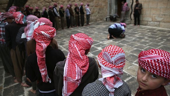Yazidi boys line up to pray at their religion's holiest temple last week in the Nineveh Province village of Lalish, Iraq.