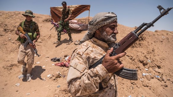 Shiite militia fighters walk along the Syrian border outside al-Badi, Iraq, earlier this year. 