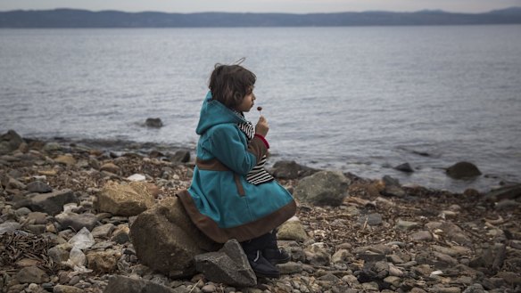 A Syrian girl eats a lollipop after her arrival on a small boat from the Turkish coast on the Greek island of Lesbos on Monday. The US had committed to increasing its Syrian refugee intake this year until the Paris attacks made politicians reconsider the plan.