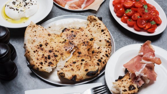 Wood-fired bread with antipasti plates of prosciutto, burrata and tomato.