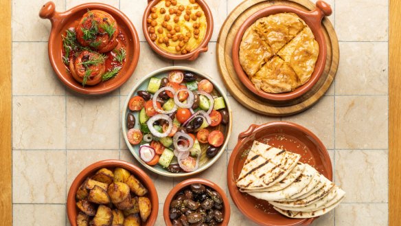 Clockwise from left: Gemista, fava dip, spanakopita, grilled pita, kalamalata olives, patates, village salad (centre). 