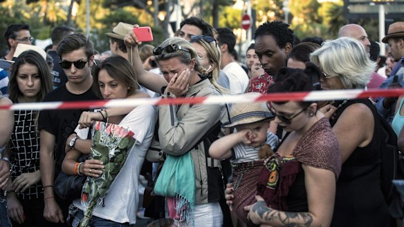 People react as they gather at a makeshift memorial near the scene of the carnage in Nice.