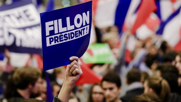 A supporter holds up a sign during an election campaign meeting for Francois Fillon in Paris.
