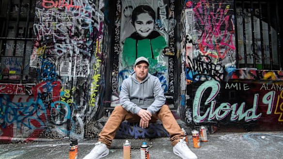 Luke Cornish in front of one of his portraits of a Syrian child. 