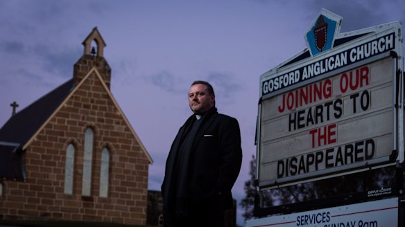 Anglican priest Father Rod Bower with the sign in front of his Gosford church which frequently features messages critical of immigration and asylum seeker policy. 7 July 2014 Photograph by Jon Reid
