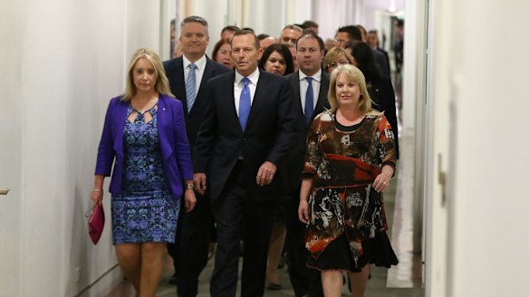 Prime Minister Tony Abbott  arrives for a partyroom meeting on the leadership flanked by supporters.