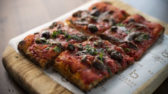 Puttanesca pizza a taglio is all crisp crust and salty, savoury topping of tomato sugo, anchovy, olives and basil.