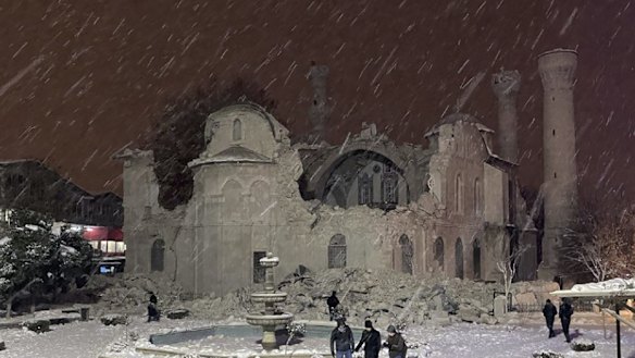 People walk next to a mosque destroyed by an earthquake in Malatya, Turkey.