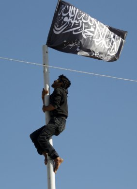 A member of al-Qaeda's Nusra Front raises the movement's flag  in the north-western city of Ariha.