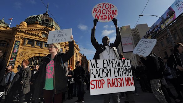 Demonstrators protesting against planned border protection raids stop traffic outside Flinders Street Station on Friday.