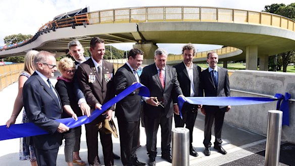 Dignitaries including Duncan Gay (with scissors) open the Albert "Tibby" Cotter walkway over ANZAC Parade earlier this year.