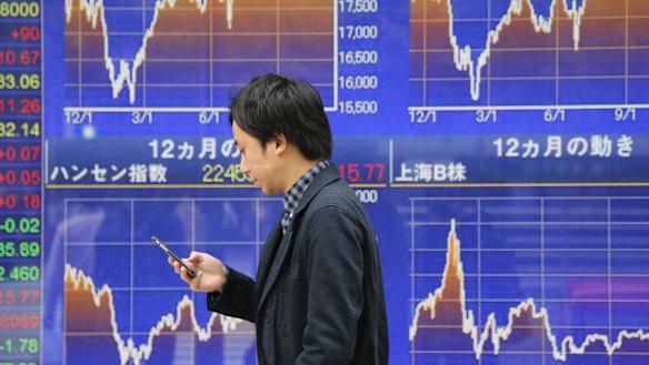 Asian uncertainty: A man walks by an electronic stock board of a securities firm in Tokyo.
