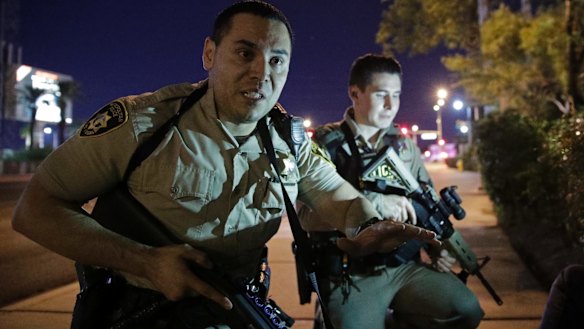 Police officers tell people to take cover near the scene of a shooting near the Mandalay Bay resort and casino on the Las Vegas Strip.