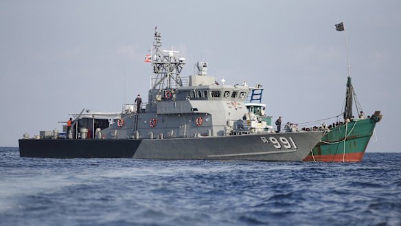 A Thai navy vessel and a migrant boat are seen tethered together in waters near Koh Lipe island