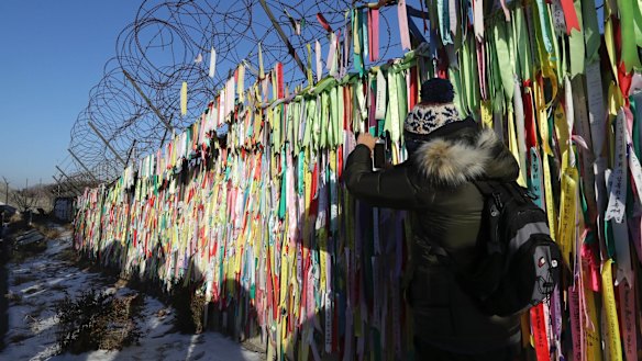 A visitor takes a photo near the North-South Korea border fence decorated with ribbons carrying messages to wish for the reunification of the two Koreas at the Imjingak Pavilion in Paju, South Korea.
