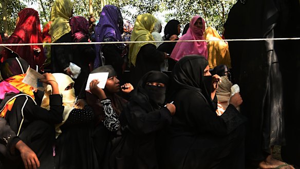 Rohingya refugee and orphan Nur Aisha, 14, sits in a queue at a Red Cross distribution point waiting for food in Bangladesh.