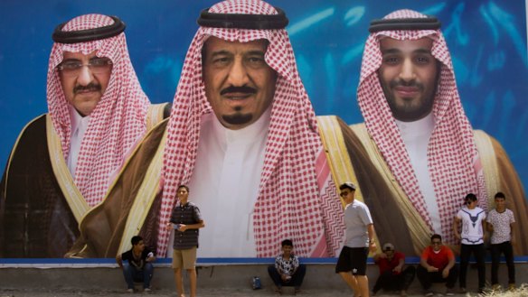Saudi boys pose in front of a huge billboard showing in the centre, King Salman, with Mohammed bin Salman to the right, and the replaced Prince Mohammed bin Nayef, left, in Taif, Saudi Arabia. 