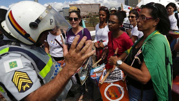 A policeman turns away a group of women hoping to join a march in Brasilia supporting a general strike, because the instruments they were carrying could be used as weapons.